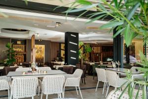 a restaurant with tables and chairs and plants at Edemus - Motel & Restaurant in Maglaj
