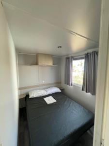 una piccola stanza con un letto e una finestra di Mobil-home 2 chambres côté rivière a Ébreuil