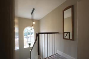 einen Flur mit einer Treppe mit einem Spiegel und einem Fenster in der Unterkunft 1 Manor Cottage, Ainderby Steeple, DL7 9PX in Northallerton