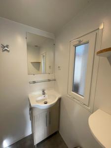 un bagno bianco con lavandino e specchio di Mobil-home 2 chambres côté rivière a Ébreuil