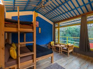 a room with two bunk beds and a table at The Hosteller Mussoorie By the Streamside, Kempty in Mussoorie