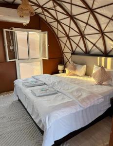 a bedroom with a large white bed with an arched ceiling at The oasis chalet in Badīyah +7 photos
