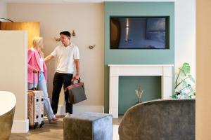 Un hombre y una mujer caminando por una sala de estar con chimenea. en Fairlawns, Hotel And Spa, en Walsall