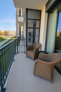 two wicker chairs sitting on the balcony of a building at Waterfront Cosy Studio Nest in Sajmište +3 photos