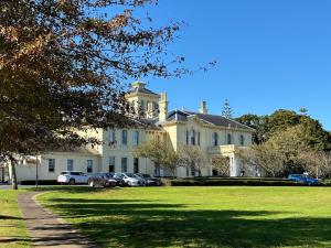 a large white house with cars parked in front of it at Lilypad of Three Kings Guest Rooms in Auckland