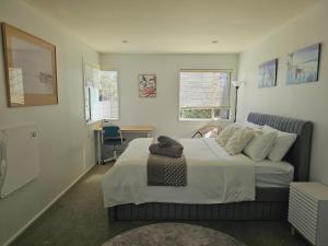 a bedroom with a bed and a desk and windows at Lilypad of Three Kings Guest Rooms in Auckland