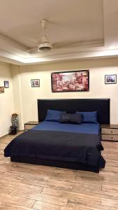 a bedroom with a large bed with blue sheets at Modern 1BR Apartment Bahria Heights 1 in Rawalpindi