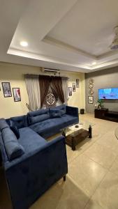 a living room with a blue couch and a flat screen tv at Modern 1BR Apartment Bahria Heights 1 in Rawalpindi