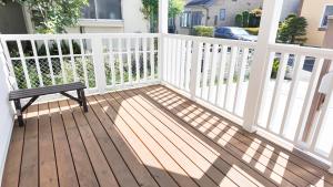 a bench sitting on a porch with a white fence at 9Stay辻堂 in Chigasaki