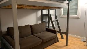 eine Couch unter einem Hochbett mit einer Leiter in der Unterkunft Quiet in Poissy city center for work or family stay in Poissy