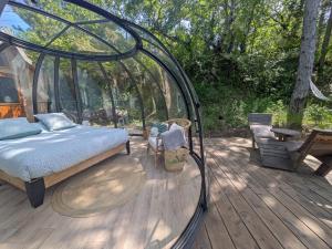 a bed in a glass house on a wooden deck at Bulles d'Olive Olea - Piscine & Jacuzzi avec vue in Nyons