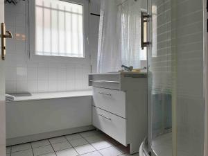 ein weißes Badezimmer mit Waschbecken und Dusche in der Unterkunft Quiet in Poissy city center for work or family stay in Poissy + 9 Fotos