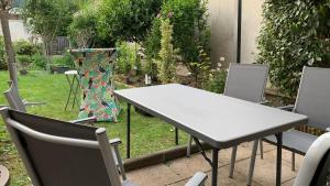 einen weißen Tisch und Stühle in einem Garten mit einem Tisch und Stühlen in der Unterkunft Quiet in Poissy city center for work or family stay in Poissy
