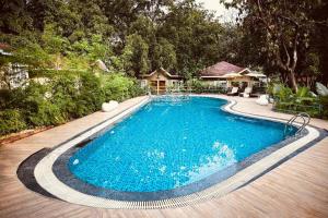 a swimming pool in a yard with a house at Neelam Foresteria Resort in Pachmarhī
