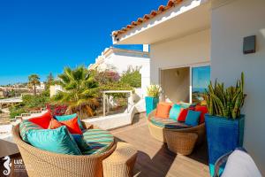 a patio with wicker chairs and colorful pillows at 180 degree Ocean Views, Pure Paradise in Luz