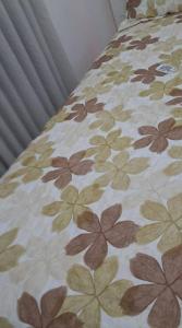 a bed with a flowered comforter on it at APARTAMENTO KOBRASOL - Bem localizado in São José