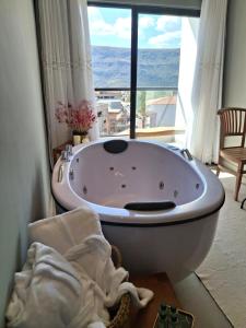 een badkuip in een kamer met een groot raam bij Hotel Verdes Mares in Ouro Branco