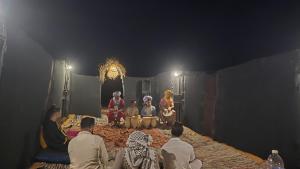 a group of people sitting on a stage at Nomada Desert Camp in Merzouga