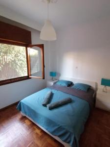 a bedroom with a bed with blue sheets and a window at Cosy house Stratoni Chalkidiki 300m from beach in Stratónion
