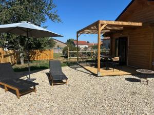 a patio with two chairs and an umbrella and a table at Chalet Champ'&Bois in Blumeray