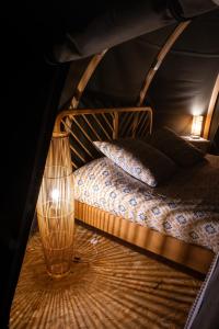a bed in a tent with a lamp and pillows at Bulles d'Olive Provence - Piscine & Jacuzzi avec vue in Nyons