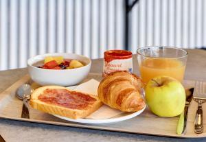 a tray with a plate of bread and a bowl of fruit and an apple at B&B HOTEL Moulins Avermes in Avermes +28 photos