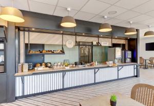 a restaurant with a counter with food on it at B&B HOTEL Moulins Avermes in Avermes