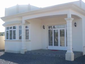 ein weißes Haus mit einer Eingangstür und Fenstern in der Unterkunft Kaz Resident in Plaine Magnien