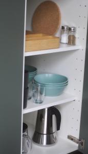 a kitchen shelf with bowls and plates and a coffee pot at L'instant bucolique in Origny-en-Thiérache