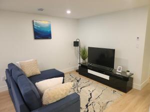 a living room with a blue couch and a flat screen tv at Zeemah Lodge in Moncton