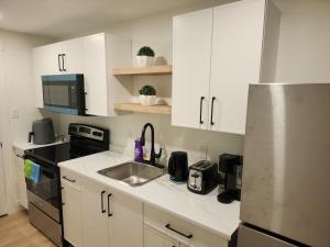 a kitchen with white cabinets and a sink at Zeemah Lodge in Moncton