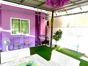 Una habitación con una pared morada y césped verde. en Warisa Grand 3 bedroom Villa, en Pattaya South
