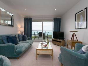een woonkamer met blauwe banken en een televisie bij Far Cliffs in St Ives