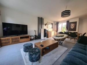 a living room with a couch and a tv at Maison Gallardon in Gallardon