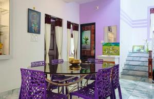a purple dining room with a glass table and purple chairs at Leland Homestay in Mararikulam