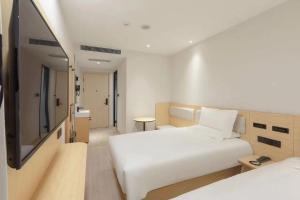 a hotel room with two beds and a flat screen tv at Hi Inn Beijing Daxing Zaoyuan Subway Station in Beijing
