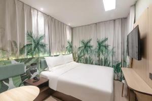 a bedroom with a white bed and a mural of palm trees at Hi Inn Beijing Daxing Zaoyuan Subway Station in Beijing