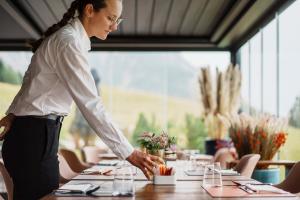a woman standing over a table in a restaurant at Casa Guargnè in Cortina dʼAmpezzo