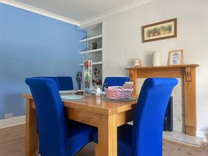 ein Esszimmer mit einem Holztisch und blauen Stühlen in der Unterkunft Gwenynen Fel Cottage in Burry Port