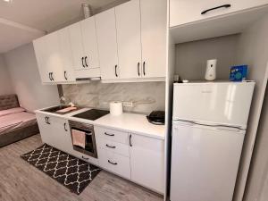 Una cocina con gabinetes blancos y un refrigerador blanco. en Urban Hideaway, en Tirana