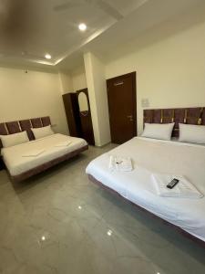 two beds in a hotel room withskirts at Uk hotel Ujjain Mahakal in Ujjain +2 photos
