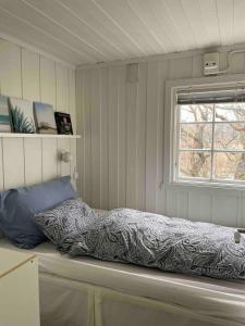ein Bett in einem Zimmer mit einem Fenster in der Unterkunft Stavern Cottage with sea views near the beach in Larvik
