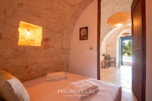 a bedroom with a bed in a stone wall at I Trulli del Tarassaco with private pool by Pregio Villas in Martina Franca +44 photos