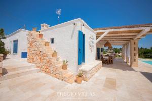 a white house with a blue door and a patio at I Trulli del Tarassaco with private pool by Pregio Villas in Martina Franca