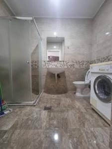 a bathroom with a tub and a toilet and a washing machine at Asisit Apartament in Kosovo Polje