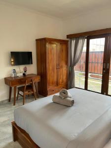 a bedroom with a bed and a desk and a television at Rumah Harmoni in Ungasan