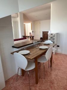 Un comedor con una mesa de madera y sillas blancas. en Mansarda Lucia, en Parma 22 fotos más