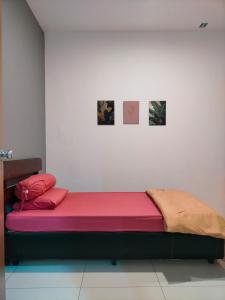 a bed in a room with two pictures on the wall at Bern's Homestay Manhattan Condo, Ipoh-GROUND FLOOR, POOLSIDE, FREE PARKING and WiFi in Ipoh
