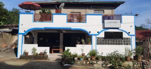 a white building with blue trim and potted plants at Eastdee Homestay - Aircon Room 108 in Lidlidda