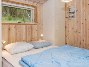 two beds in a room with wooden walls and a window at 8 person holiday home in Ebeltoft in Ebeltoft